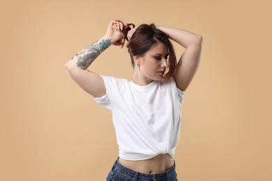 Portrait of beautiful tattooed woman on beige background
