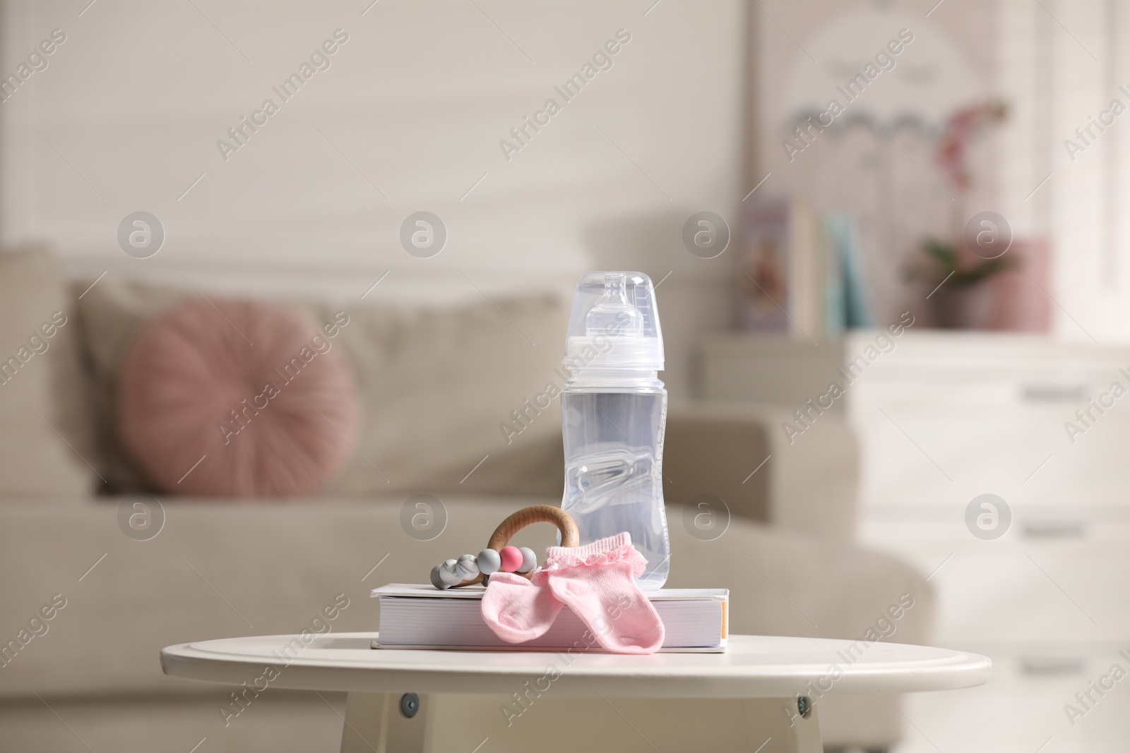 Photo of Book, baby bottle, socks and toy on white table in room. Maternity leave concept