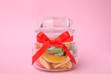 Photo of Tasty colorful jelly candies in glass jar on pink background