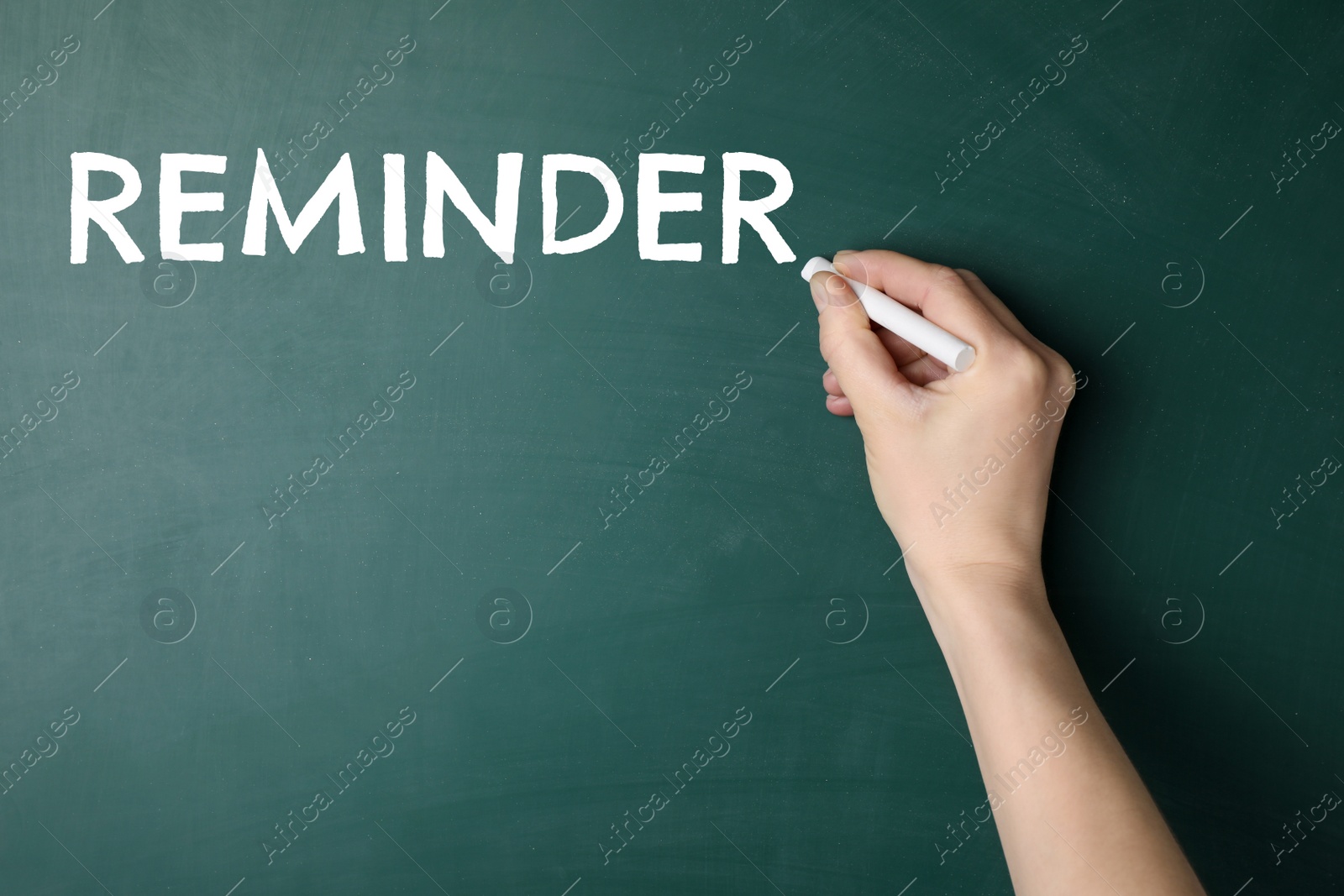 Image of Woman writing word Reminder on chalkboard, closeup