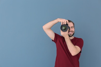 Photo of Young photographer with professional camera on color background