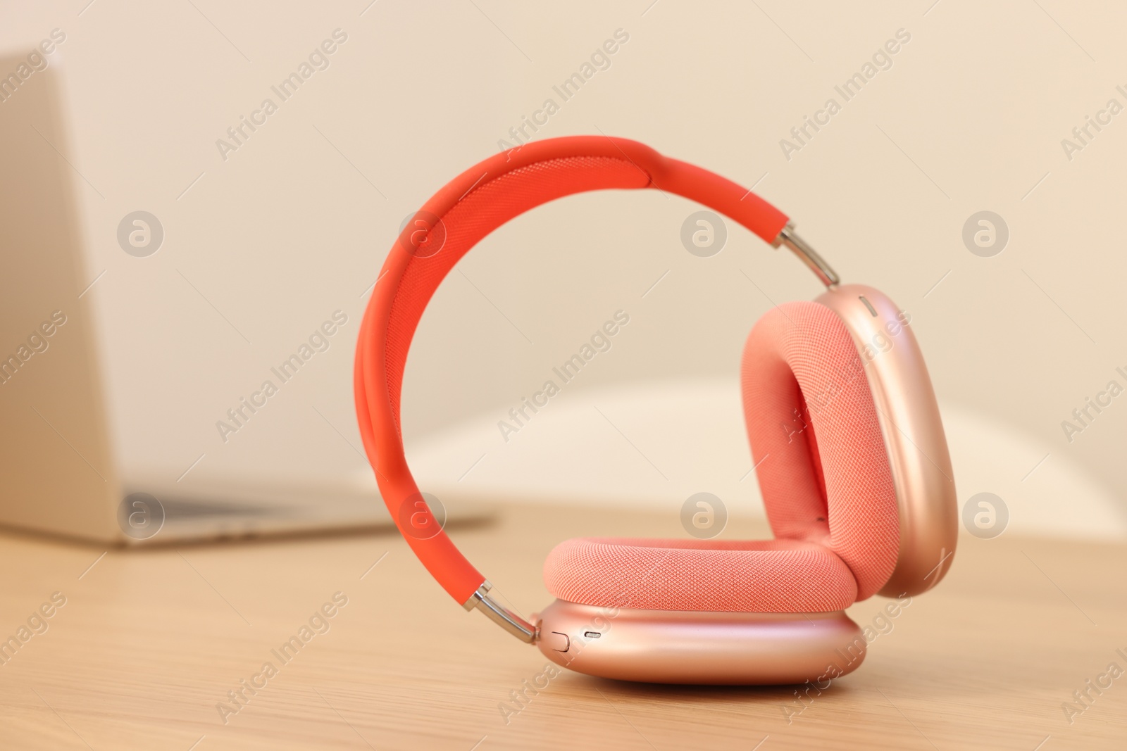 Photo of Modern headphones and laptop on wooden table