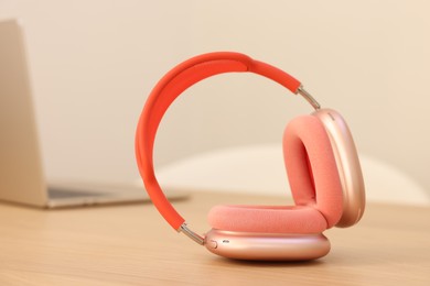 Modern headphones and laptop on wooden table