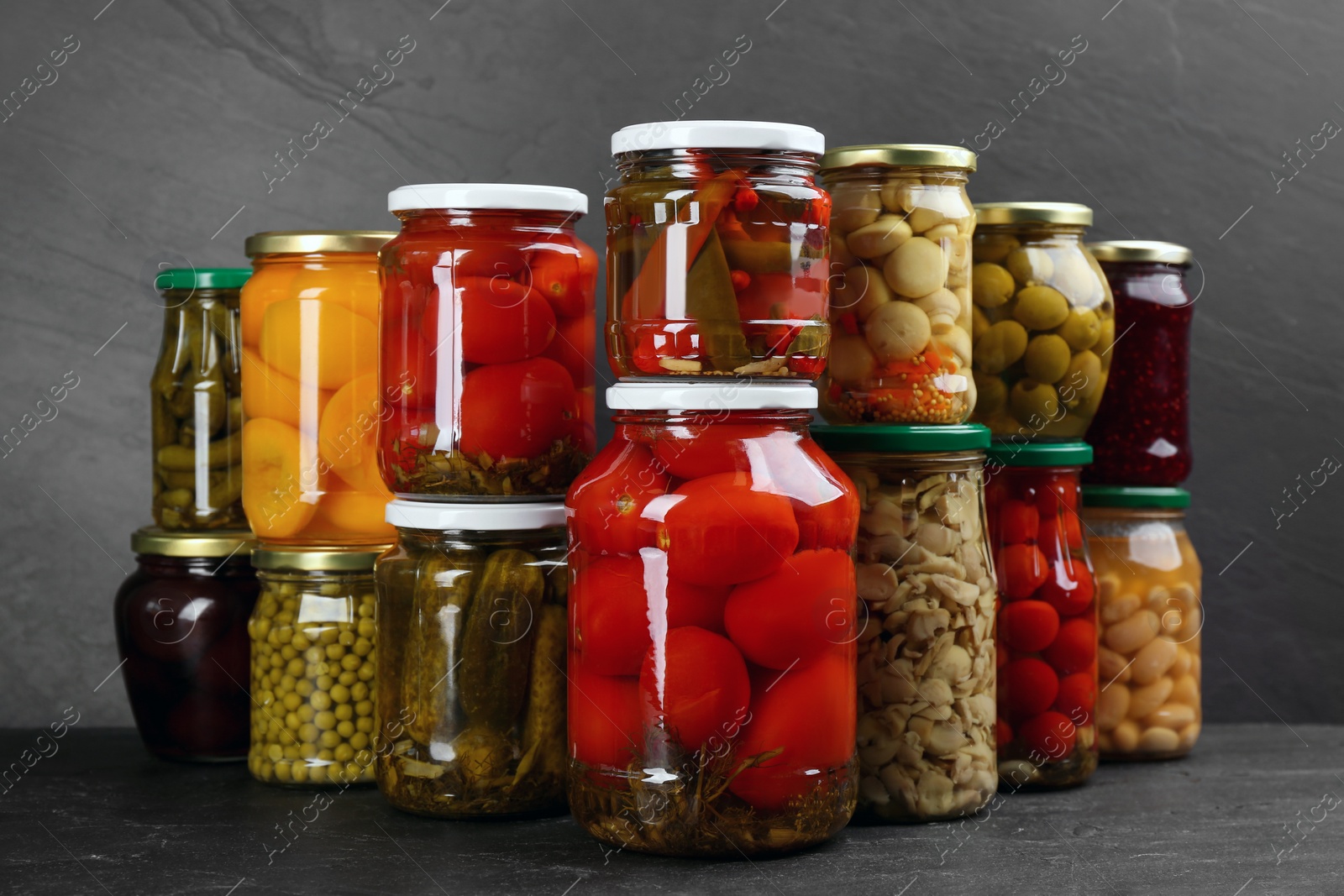 Photo of Jars of pickled vegetables on grey table