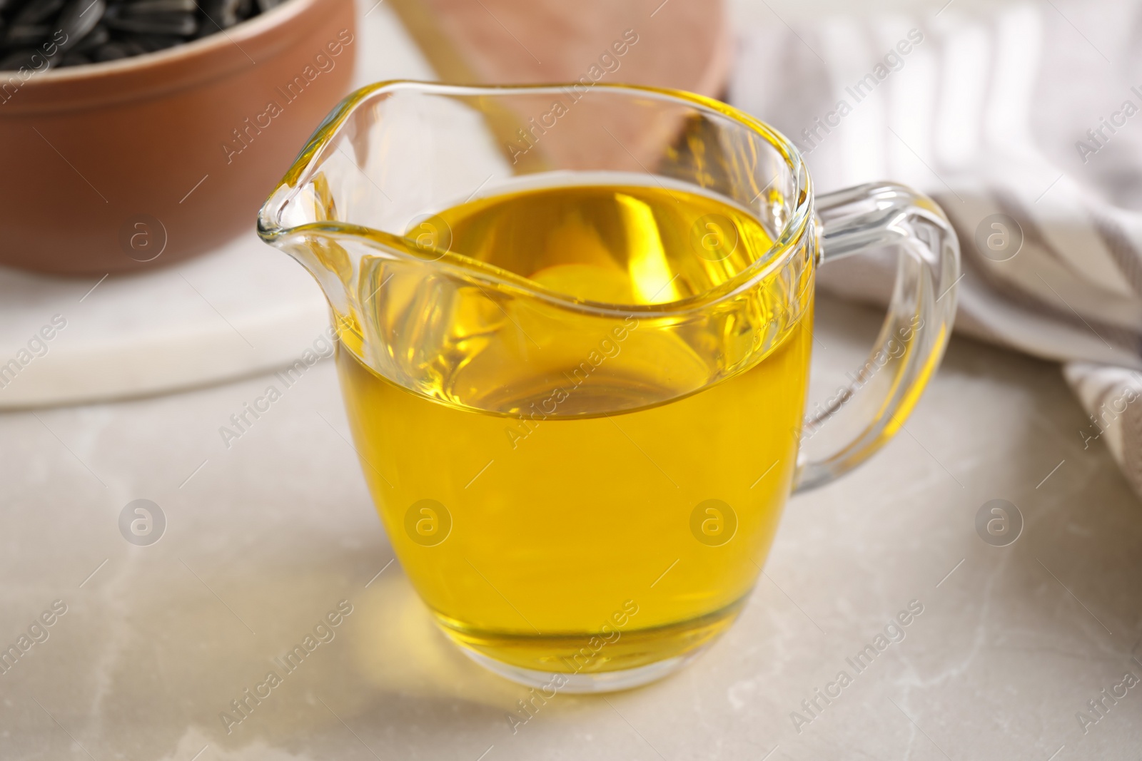 Photo of Glass jug with sunflower oil on light grey marble table