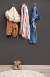 Different clothes hanging on grey wall indoors. Hallway interior elements