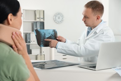 Doctor with neck MRI image consulting patient in clinic