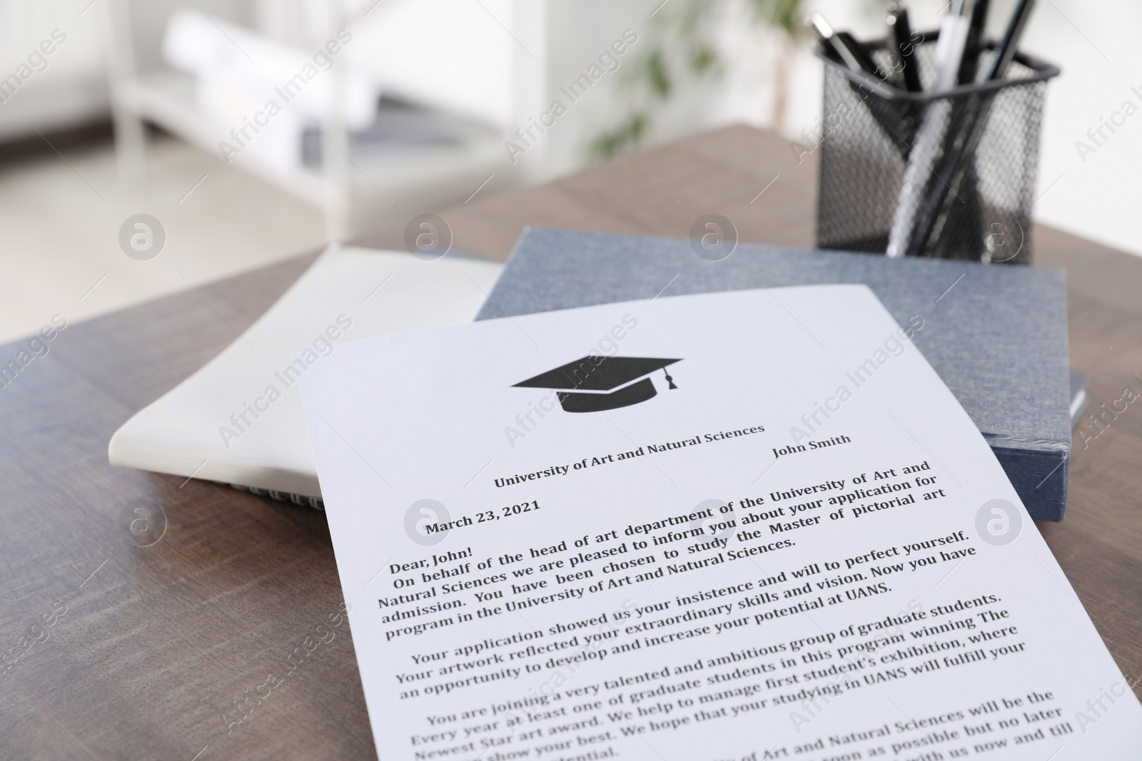 Photo of Acceptance letter from university and books on wooden table indoors, closeup