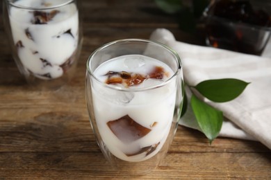 Photo of Glasses of milk with delicious grass jelly on wooden table, closeup