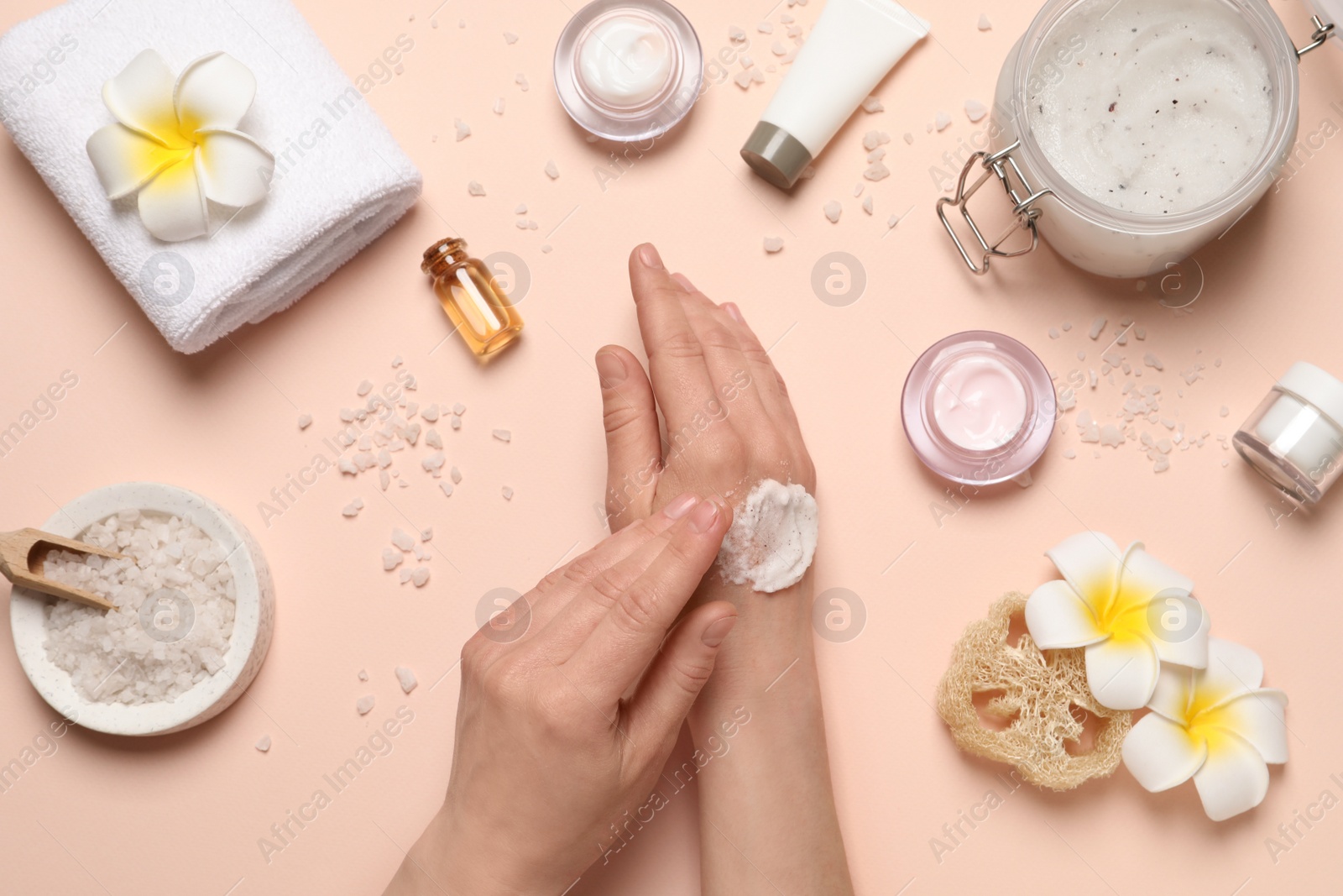 Photo of Woman applying body scrub on hand against pink background, top view