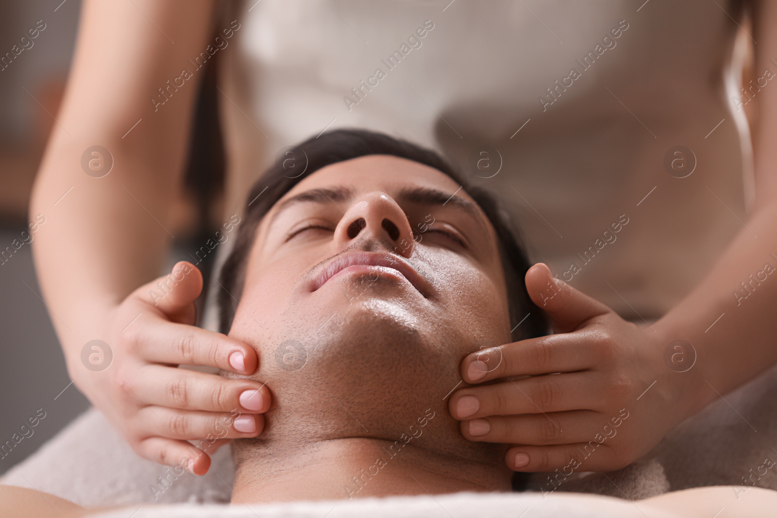 Photo of Man receiving facial massage in beauty salon, closeup