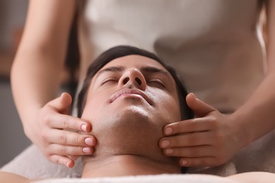 Photo of Man receiving facial massage in beauty salon, closeup