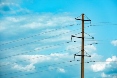 Photo of Telephone pole and wires against blue sky with clouds
