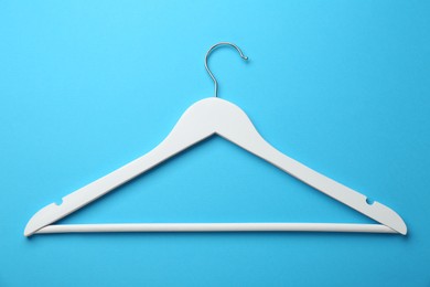 Photo of White hanger on light blue background, top view
