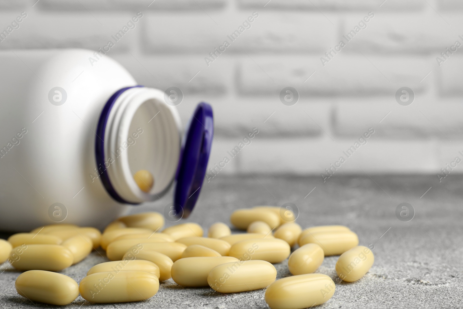 Photo of White medical bottle and pills on light gray textured table, closeup. Space for text