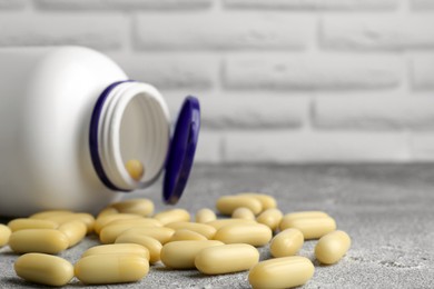 White medical bottle and pills on light gray textured table, closeup. Space for text