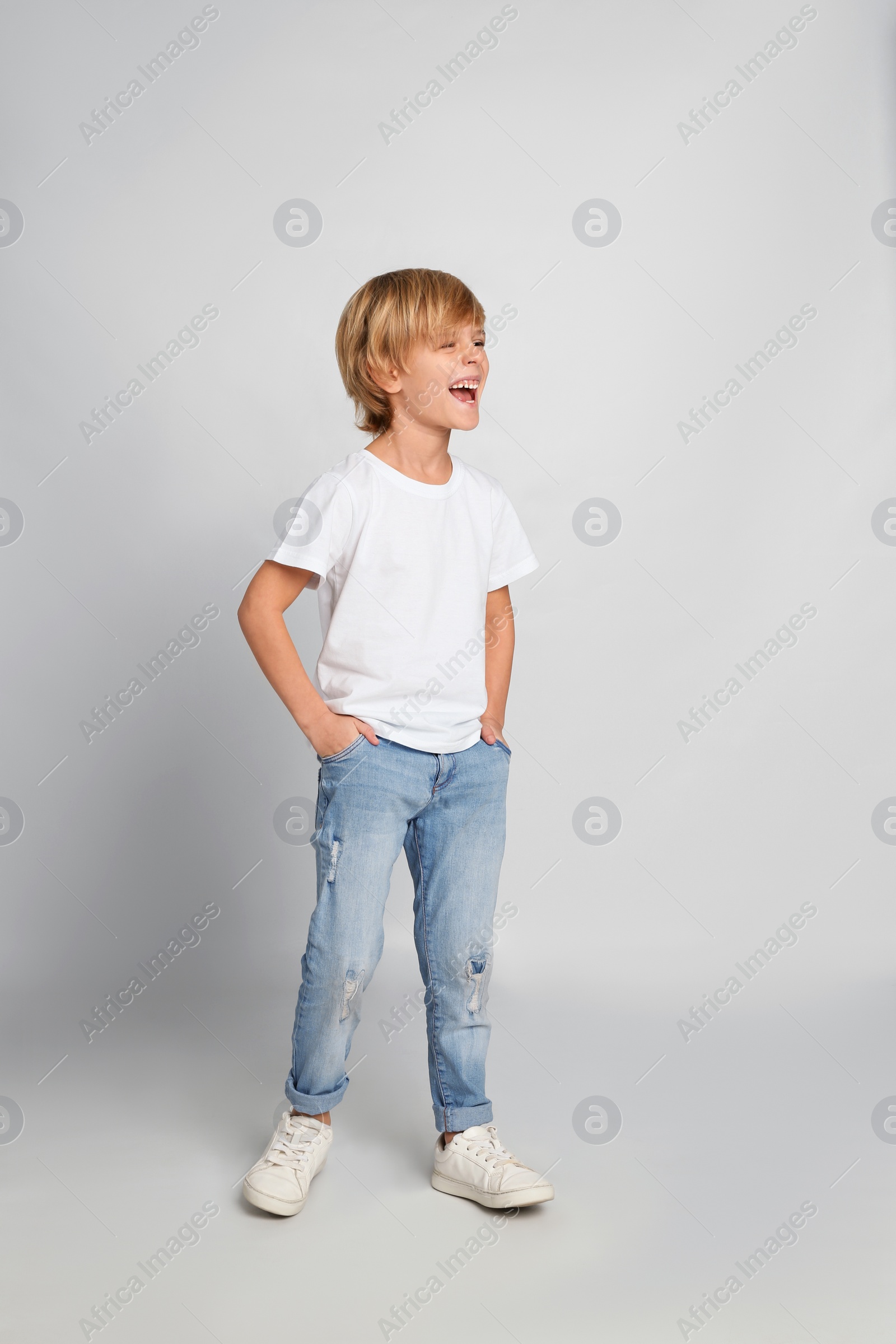 Photo of Happy little boy in casual outfit on light grey background