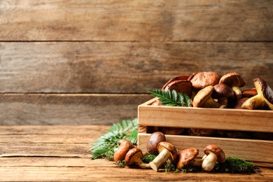Photo of Fresh wild slippery jack mushrooms in wooden crate on table. Space for text
