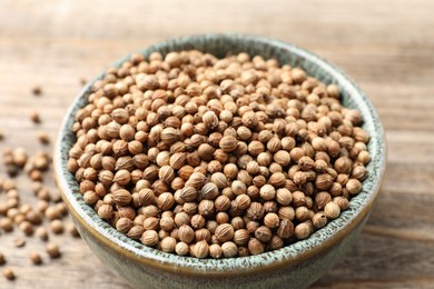 Dried coriander seeds in bowl on table, closeup