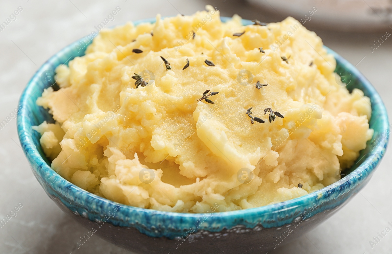 Photo of Bowl with tasty mashed potato on gray table