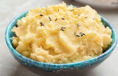 Photo of Bowl with tasty mashed potato on gray table