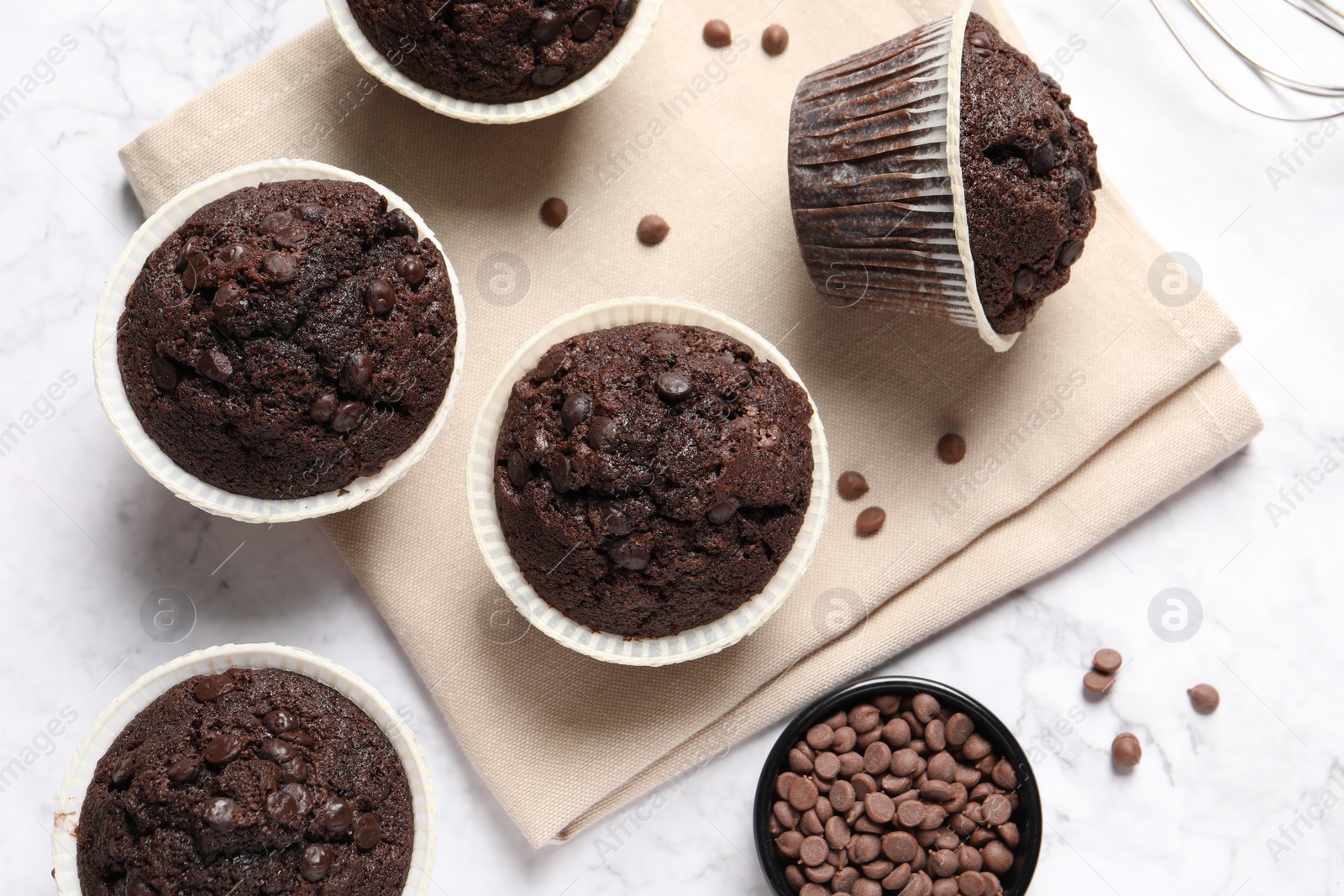 Photo of Tasty chocolate muffins on white marble table, flat lay