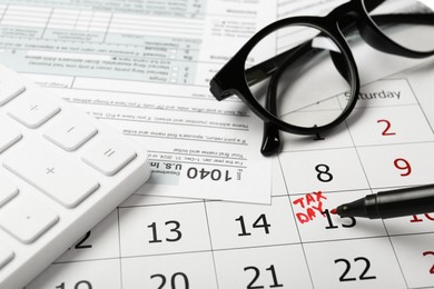 Marking tax day in calendar, felt pen, documents, glasses and calculator, closeup