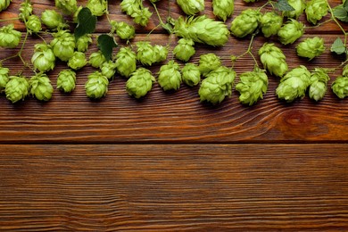 Branches of fresh green hops on wooden table, flat lay. Space for text