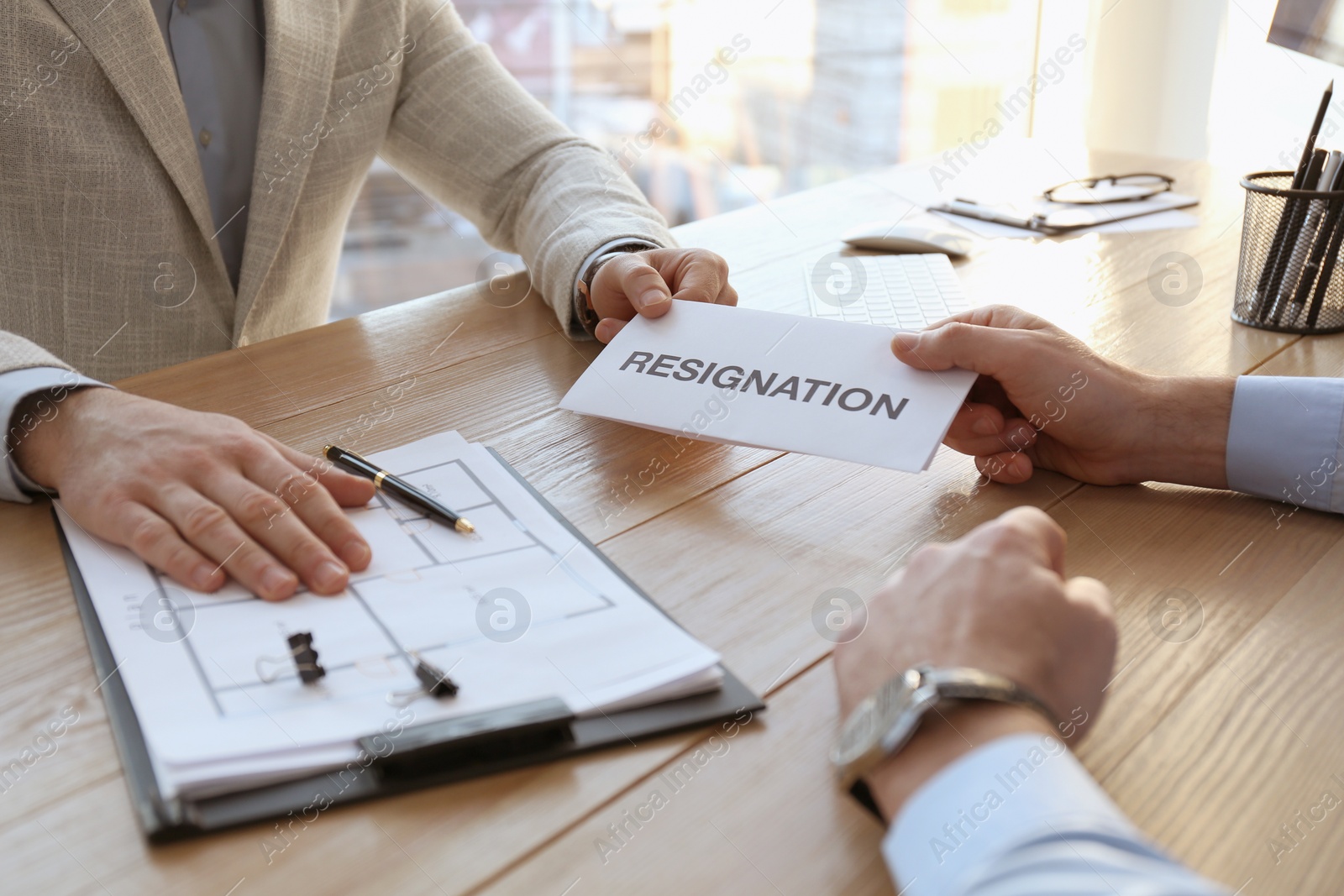 Photo of Employee giving resignation letter to boss in office, closeup