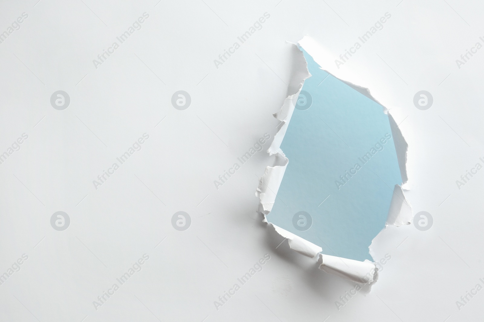 Photo of Hole in white paper on light background, space for text