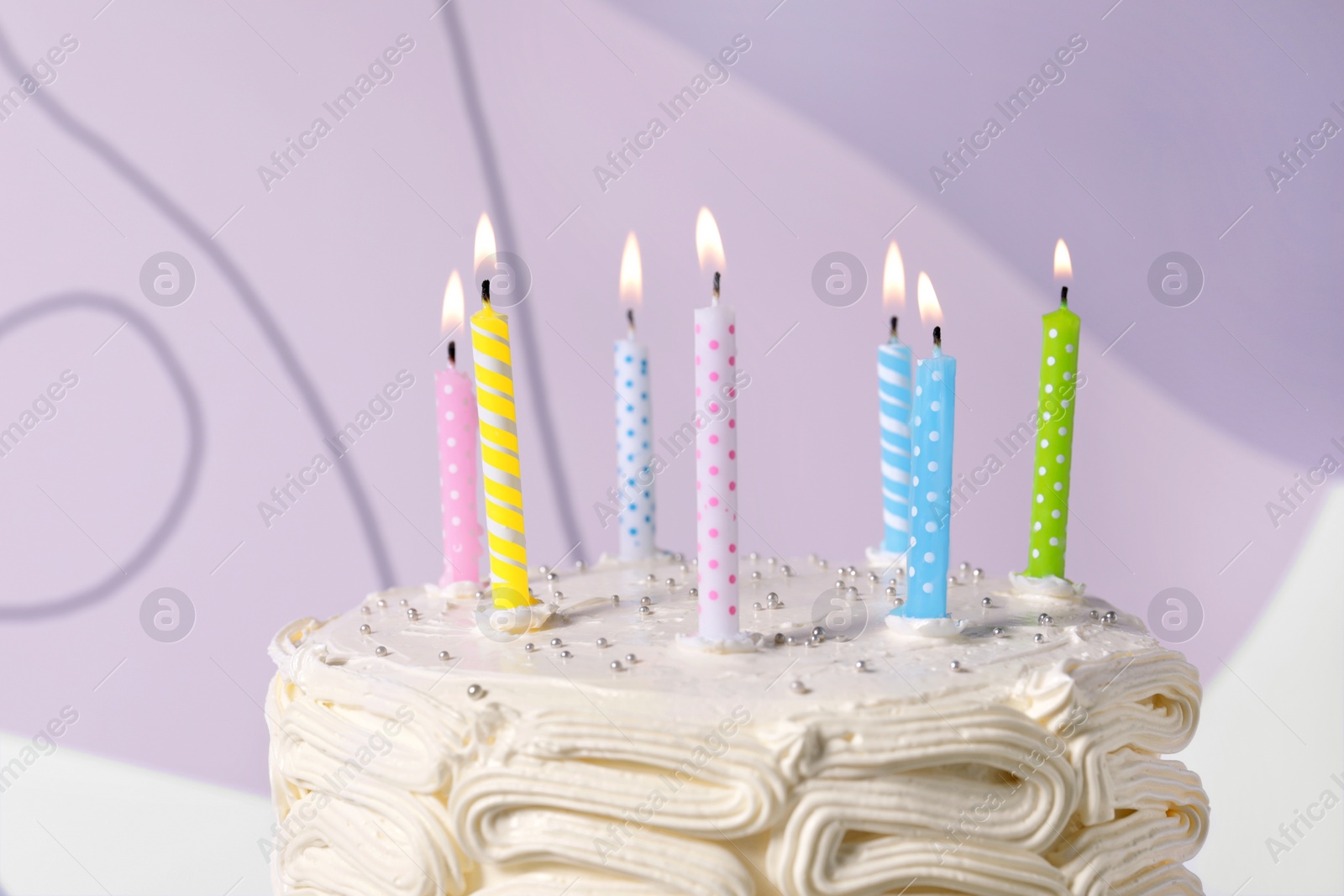 Photo of Delicious cake with cream burning candles on color background, closeup