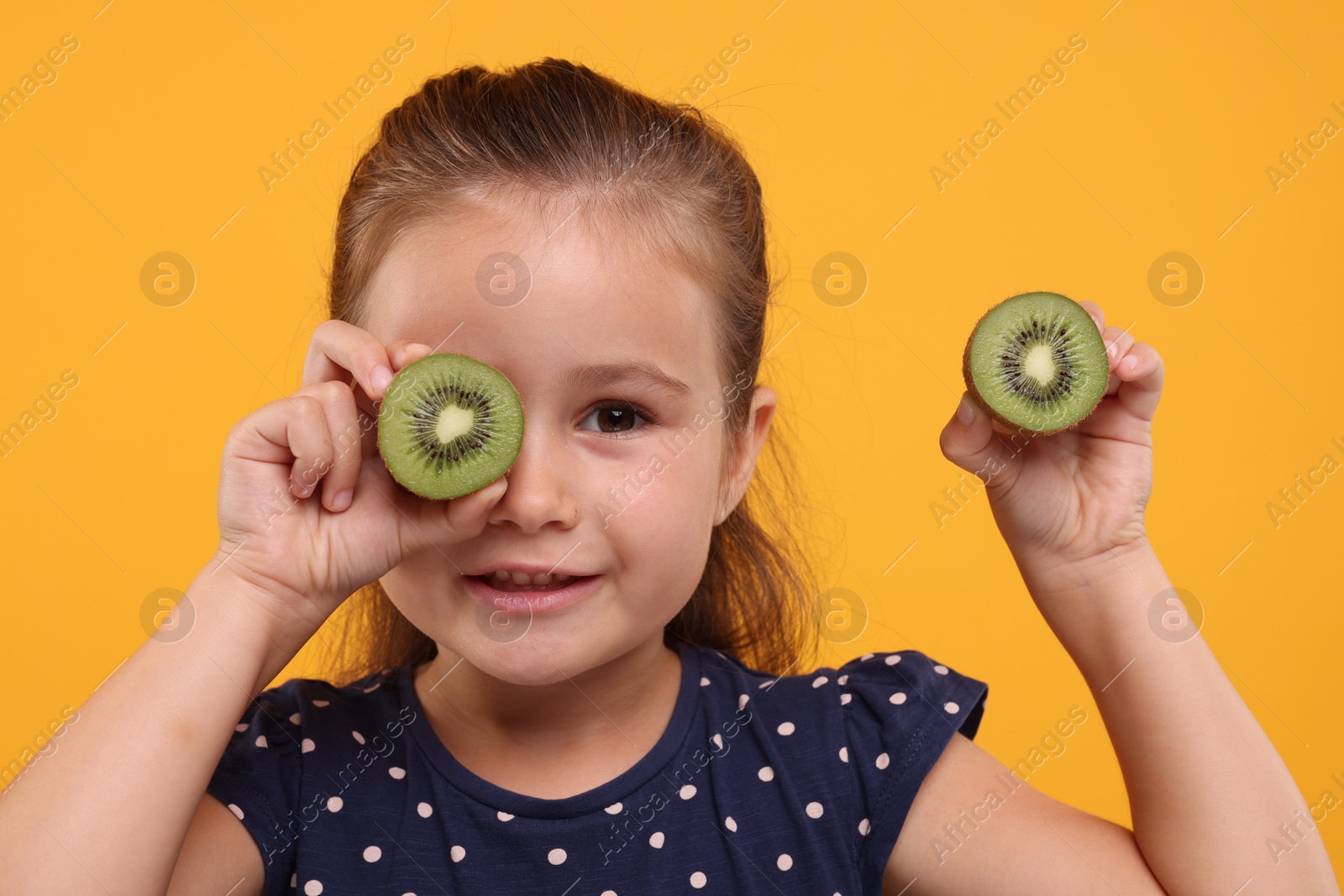 Photo of Cute girl with fresh kiwi on orange background