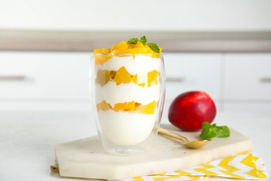 Tasty peach dessert with yogurt on white table