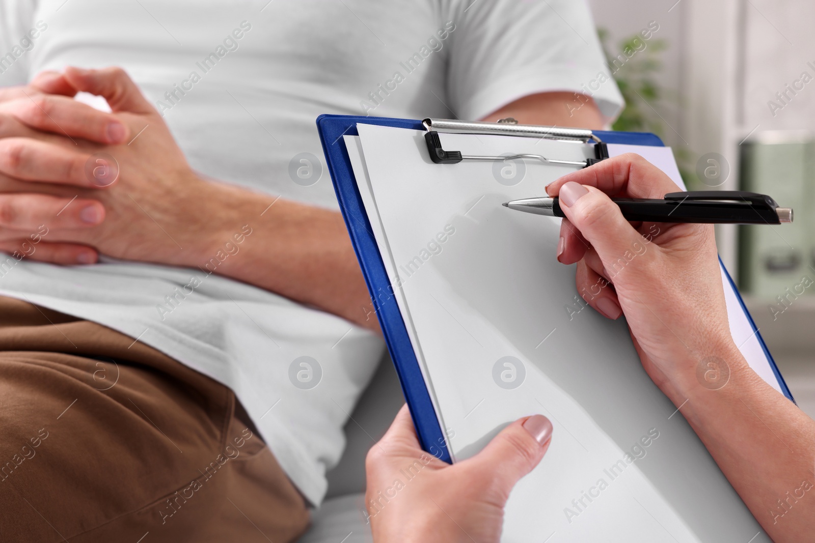 Photo of Doctor writing down patient's complaints during consultation in clinic, closeup