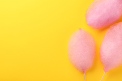 Photo of Sweet pink cotton candies on yellow background, flat lay. Space for text