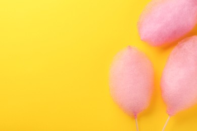 Sweet pink cotton candies on yellow background, flat lay. Space for text