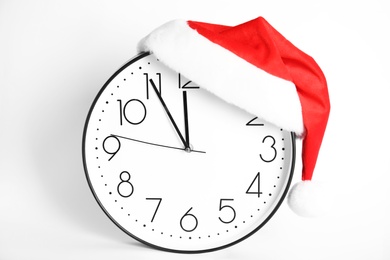 Photo of Clock with Santa hat showing five minutes until midnight on white background. New Year countdown