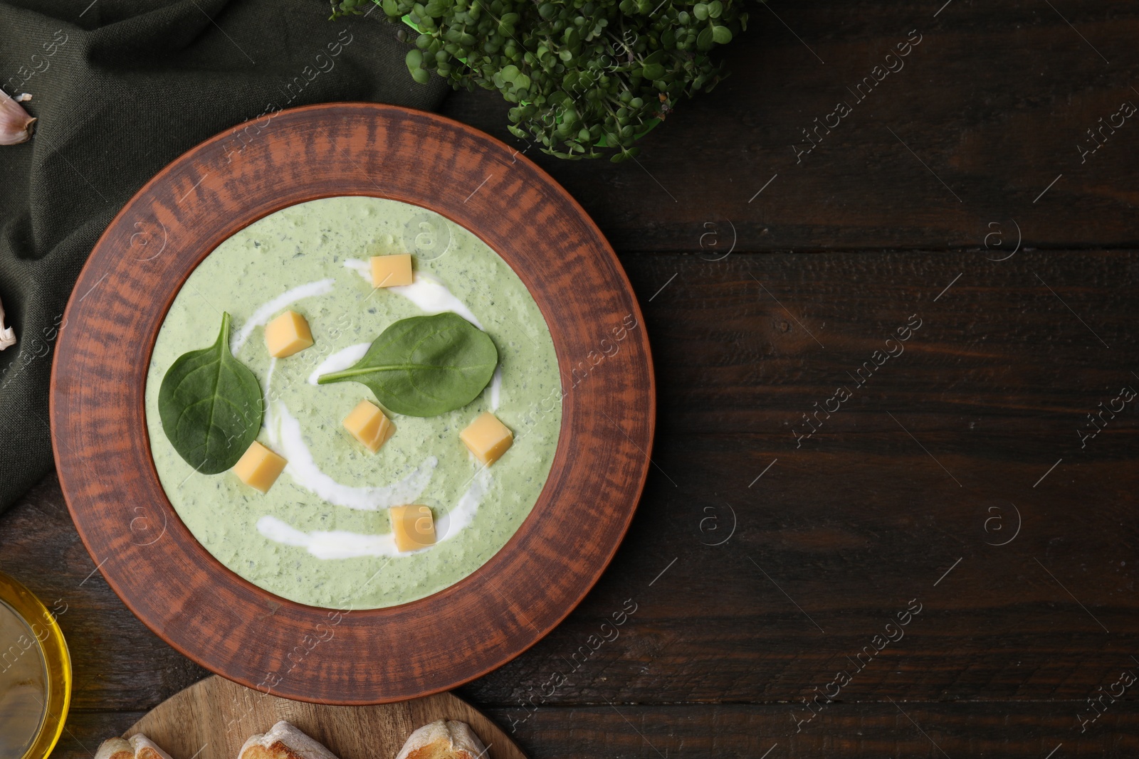 Photo of Delicious spinach cream soup with leaves and cheese in bowl on wooden table, flat lay. Space for text