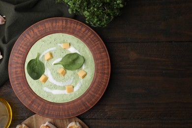 Photo of Delicious spinach cream soup with leaves and cheese in bowl on wooden table, flat lay. Space for text