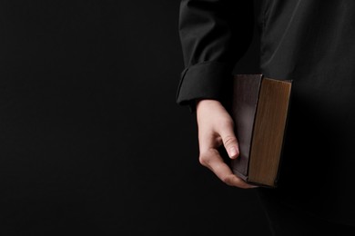Photo of Woman with holy Bible on black background, closeup. Space for text