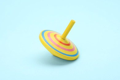 Photo of One bright spinning top on light blue background. Toy whirligig