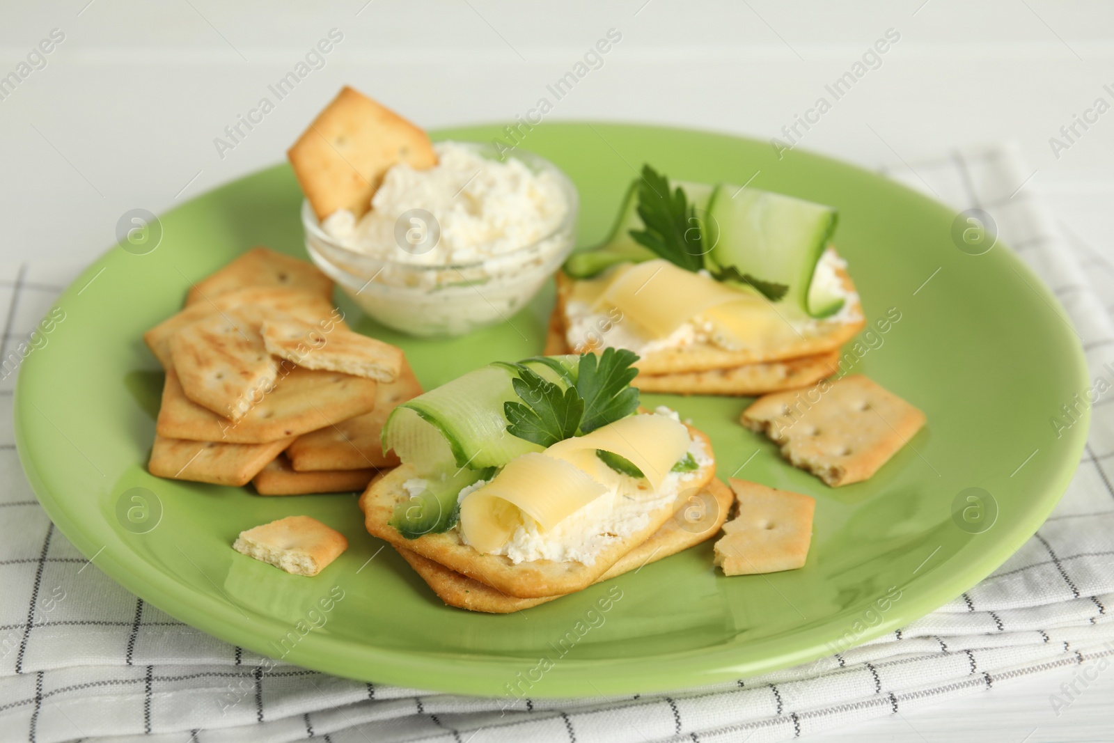 Photo of Delicious crackers with cream cheese, cucumber and parsley on white table, closeup