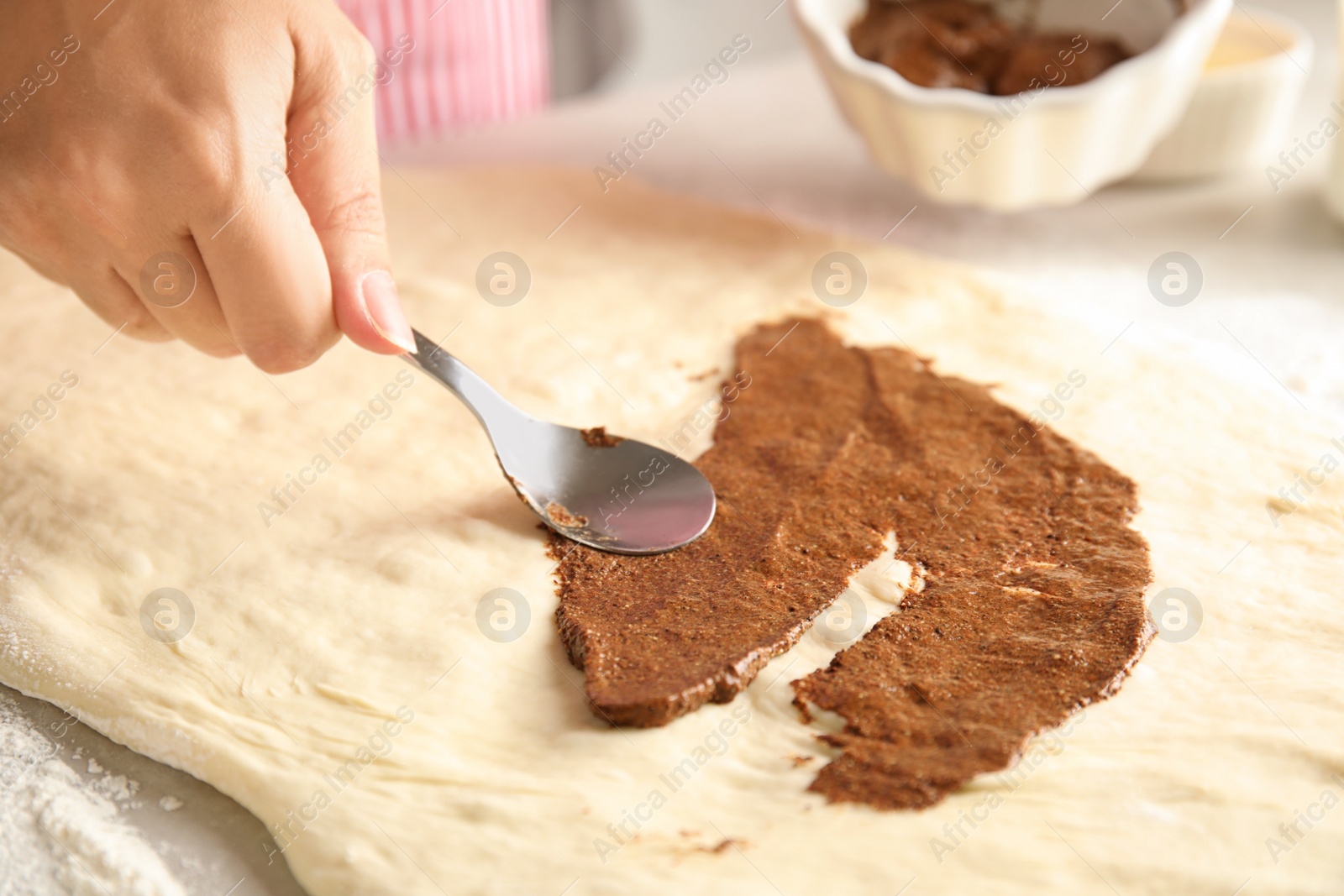 Photo of Woman making cinnamon rolls at table, closeup