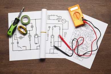 Photo of Wiring diagrams, digital multimeter and tools on wooden table, top view