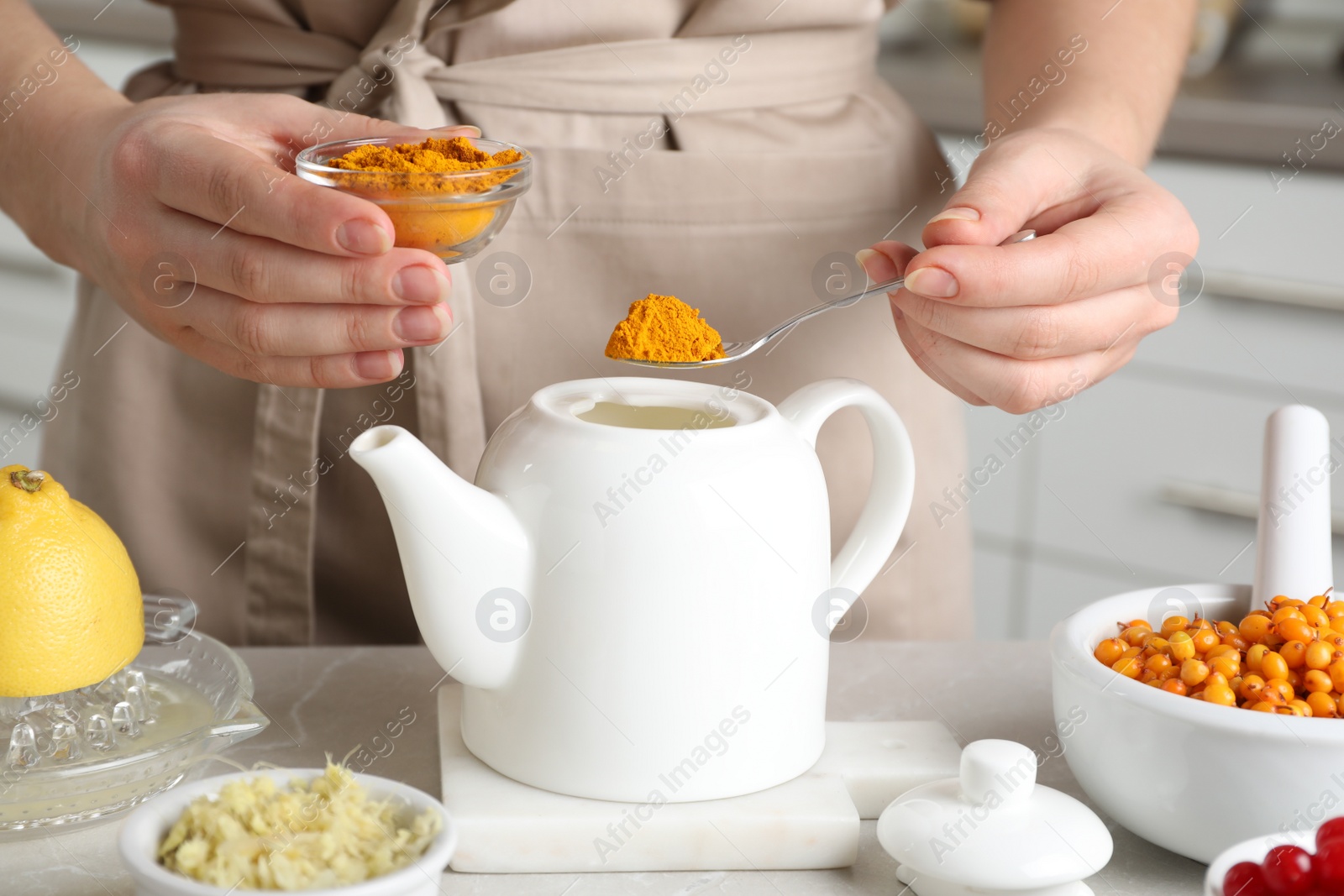 Photo of Woman making immunity boosting drink with turmeric powder at marble table, closeup