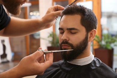 Professional hairdresser working with client in barbershop, closeup