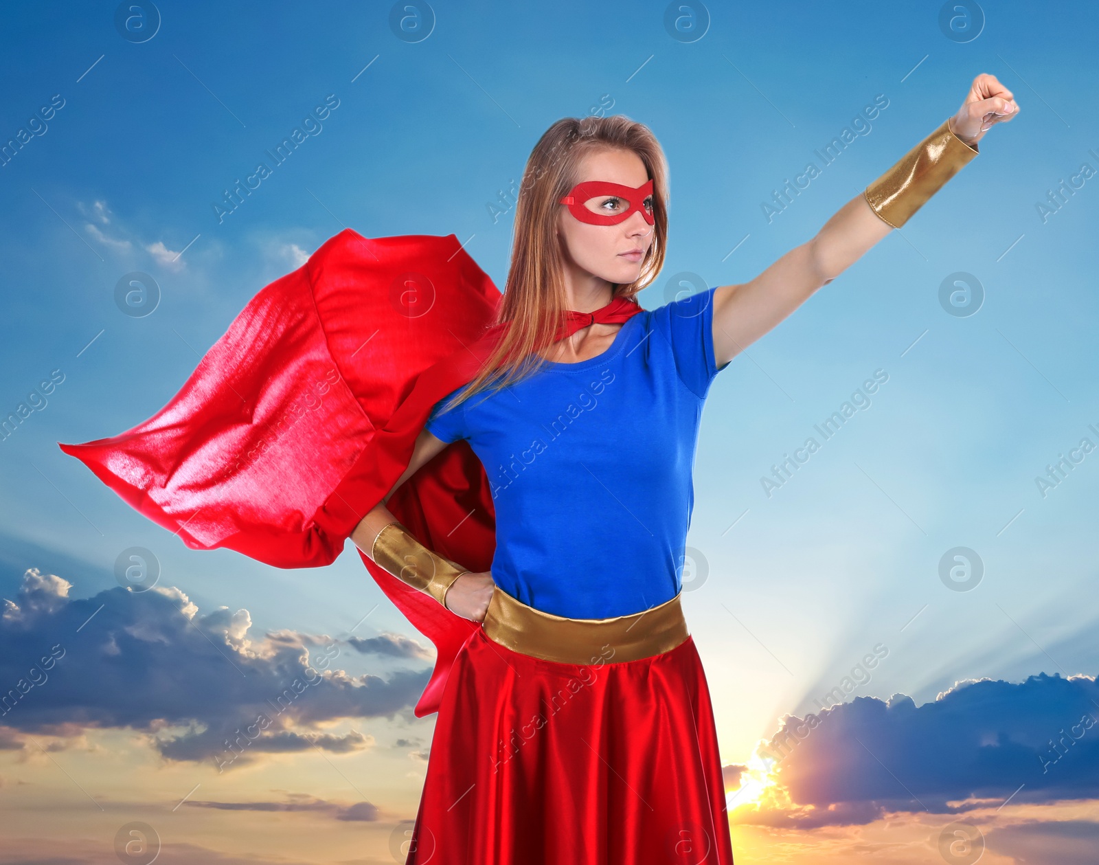 Image of Confident woman wearing superhero costume against cloudy sky