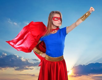 Confident woman wearing superhero costume against cloudy sky