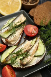 Photo of Delicious sandwiches with sprats, cucumber and dill served on plate, closeup