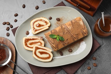 Tasty cake roll with jam and mint on grey table, flat lay